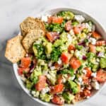 crackers on edge of bowl in avocado feta dip.