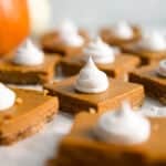 healthy pumpkin pie bars cut into squares with dollop whipped cream.
