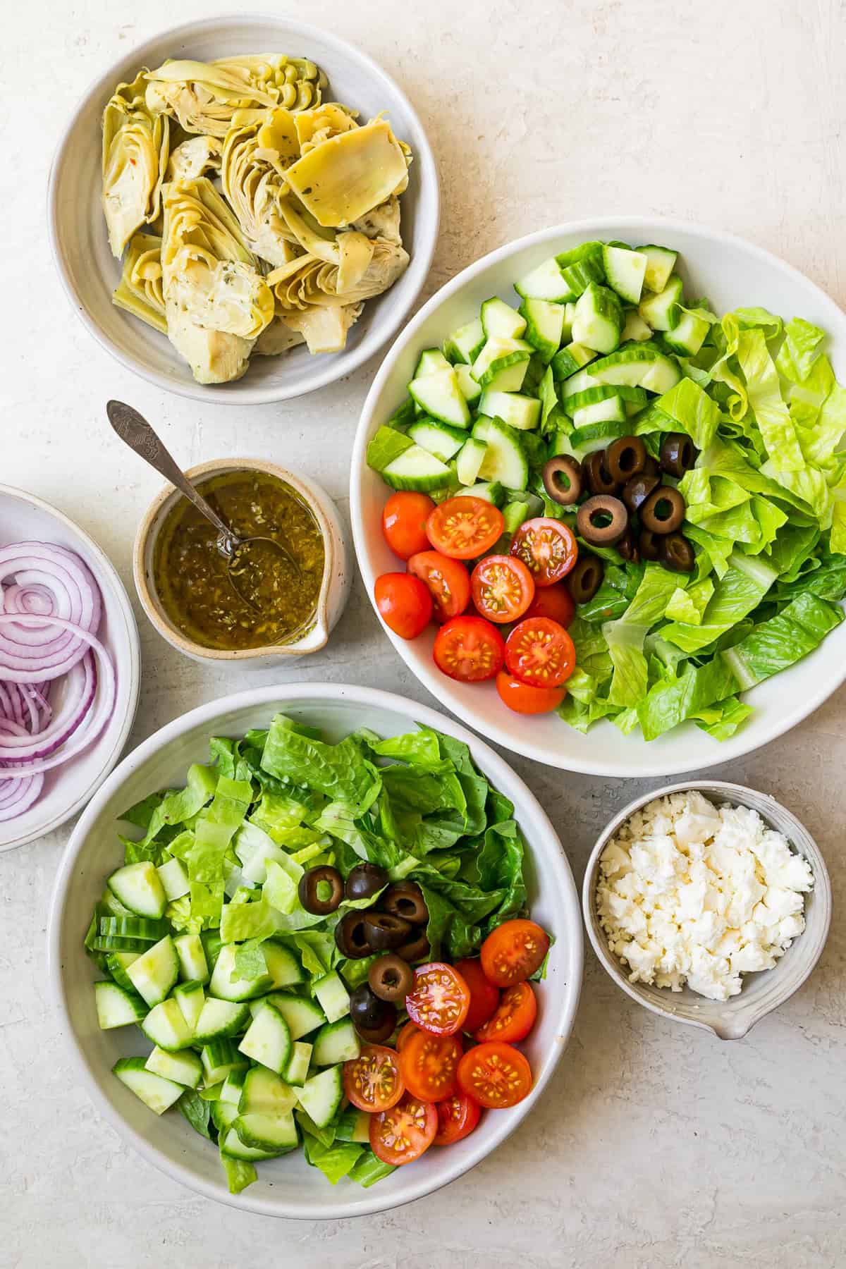 overhead view of salad bowls being assembled for a greek salmon salad