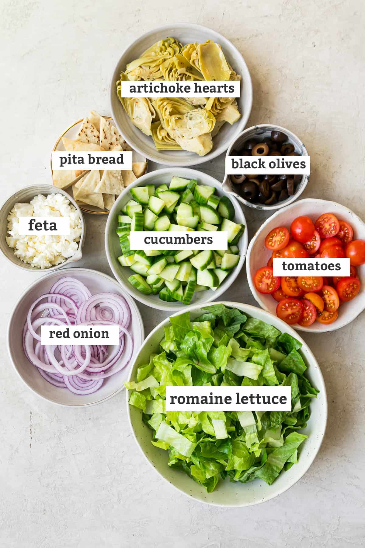 measured ingredients in bowls with text labels for a greek salmon salad recipe