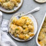 overhead view of cauliflower mac and cheese recipe on plate next to baking dish and linen.