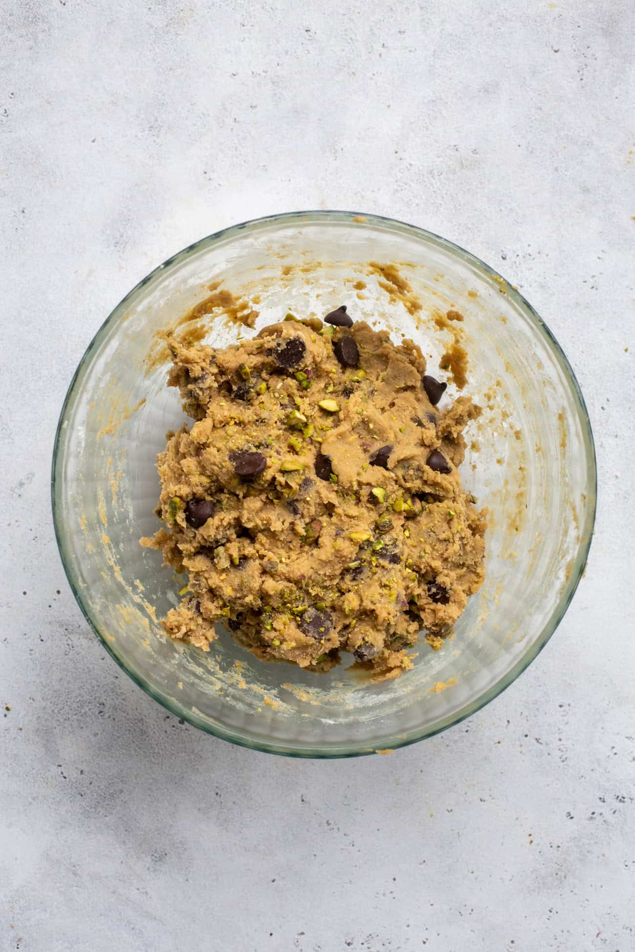 chocolate chip cookie dough with pistachios on glass bowl.