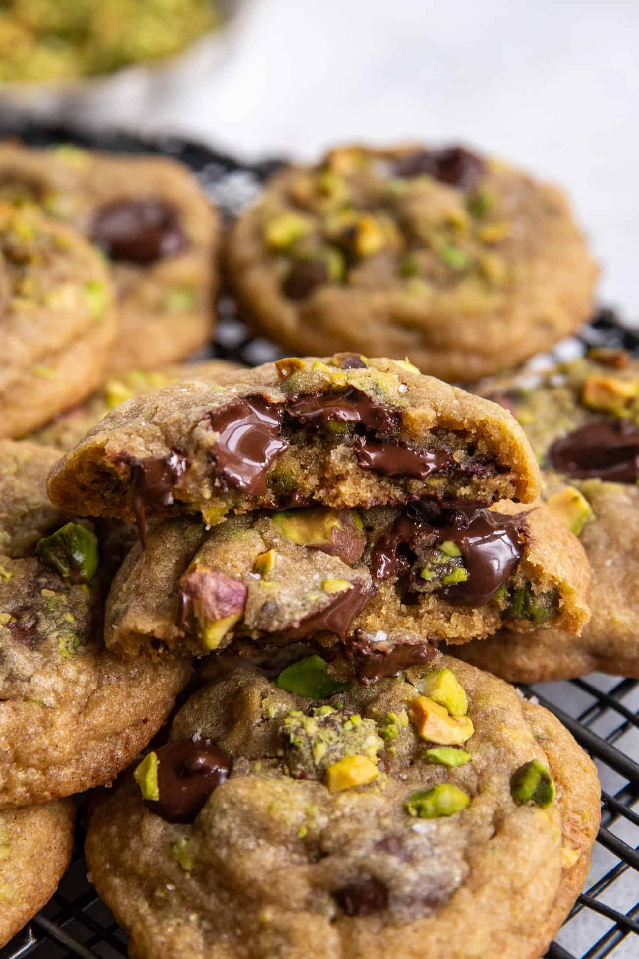 melty chocolate pistachio chocolate chip cookie on black wire rack.