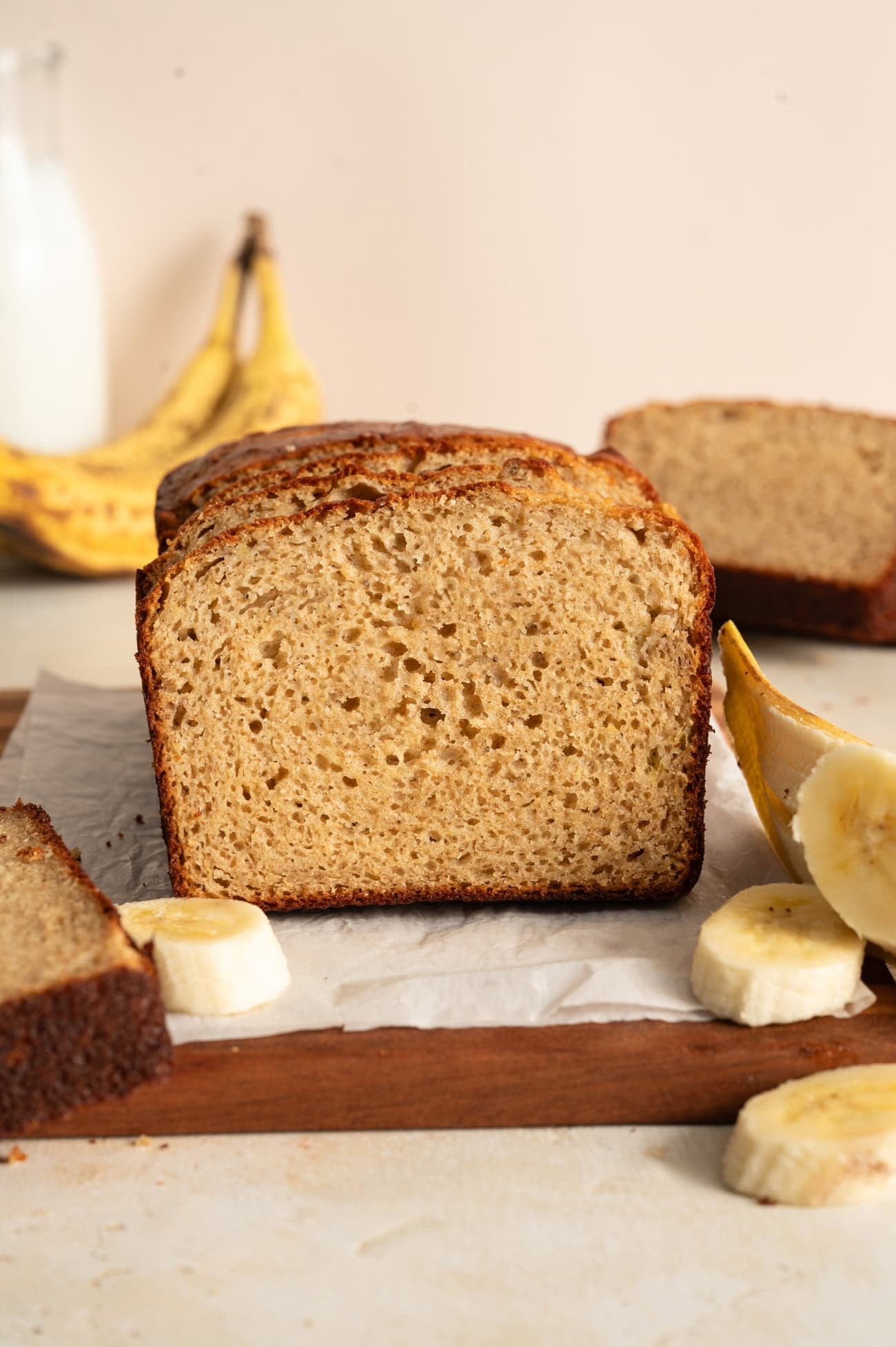straight on view of high protein banana bread on cutting board with cream background