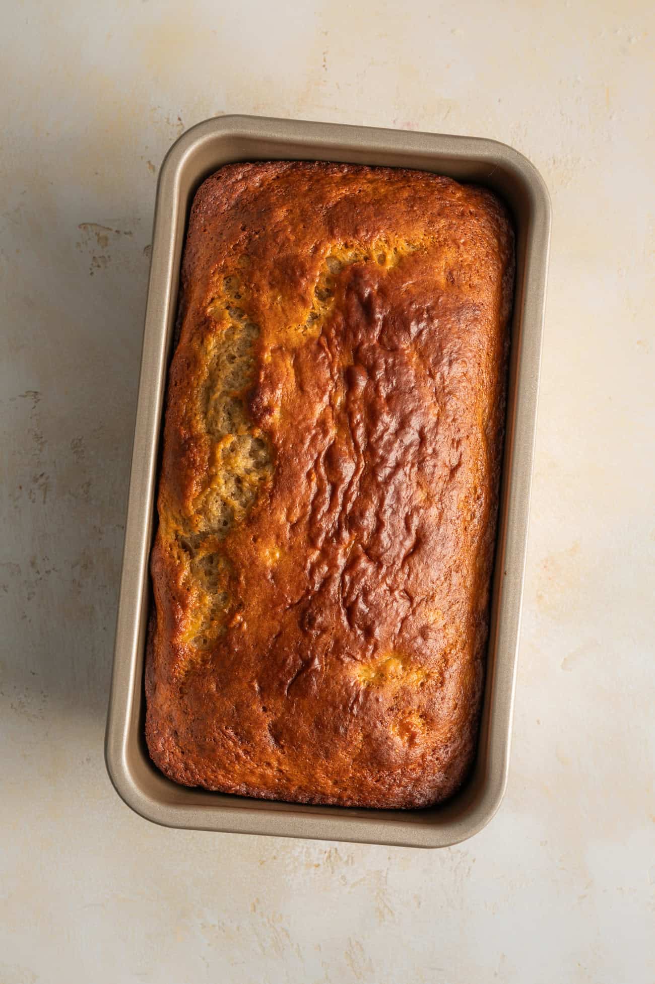 overhead view of golden banana bread loaf in pan.
