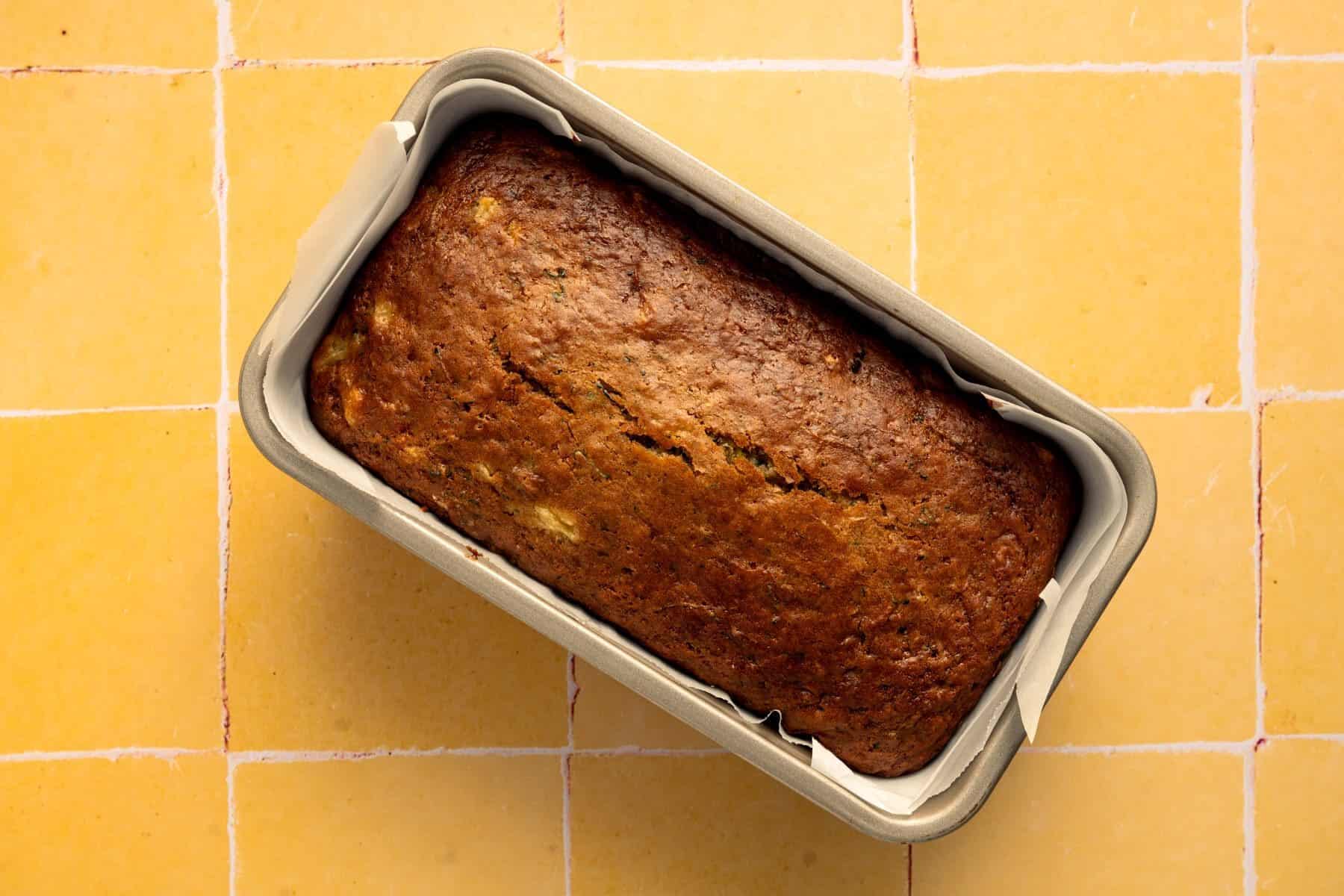 baked zucchini bread recipe with pineapple on yellow tile.