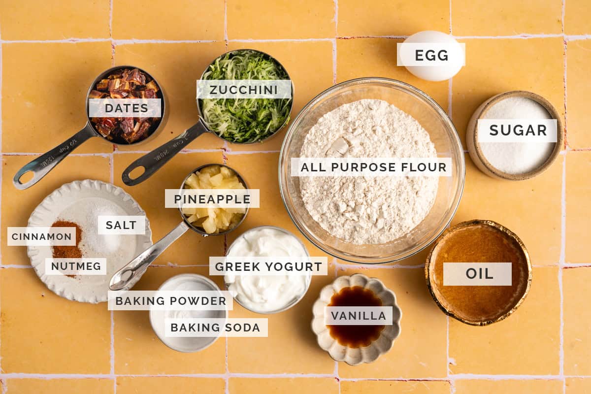 zucchini bread ingredients on yellow tile backdrop.