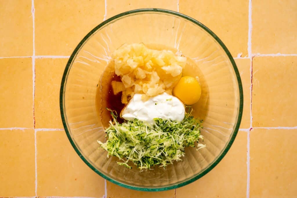 zucchini and pineapple with wet ingredients in glass bowl.