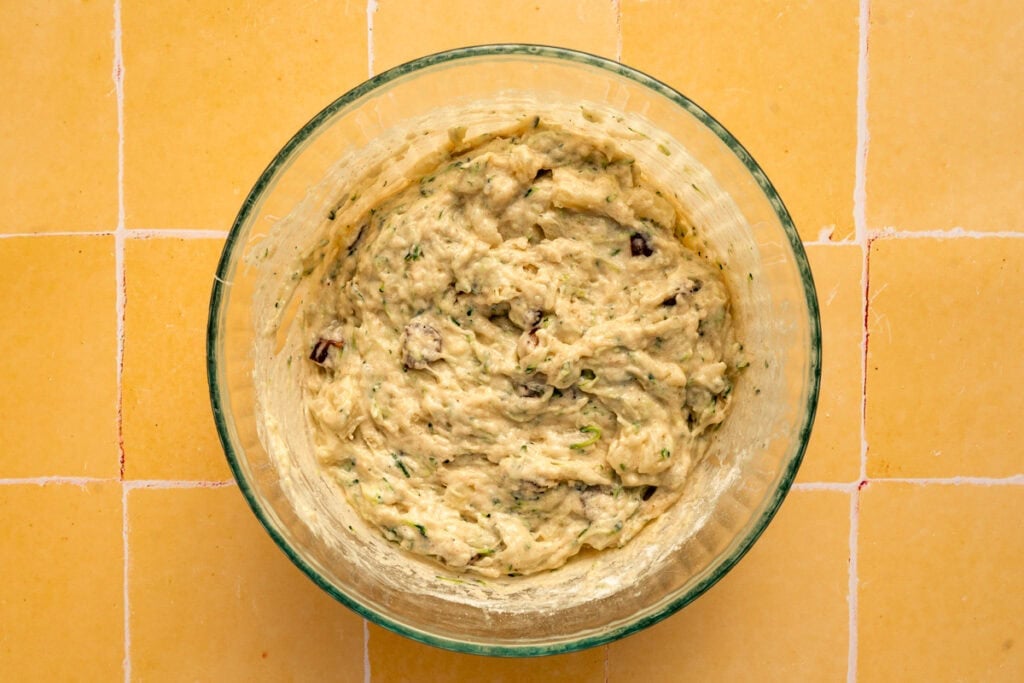quick bread batter mixed together in glass bowl on yellow tile.