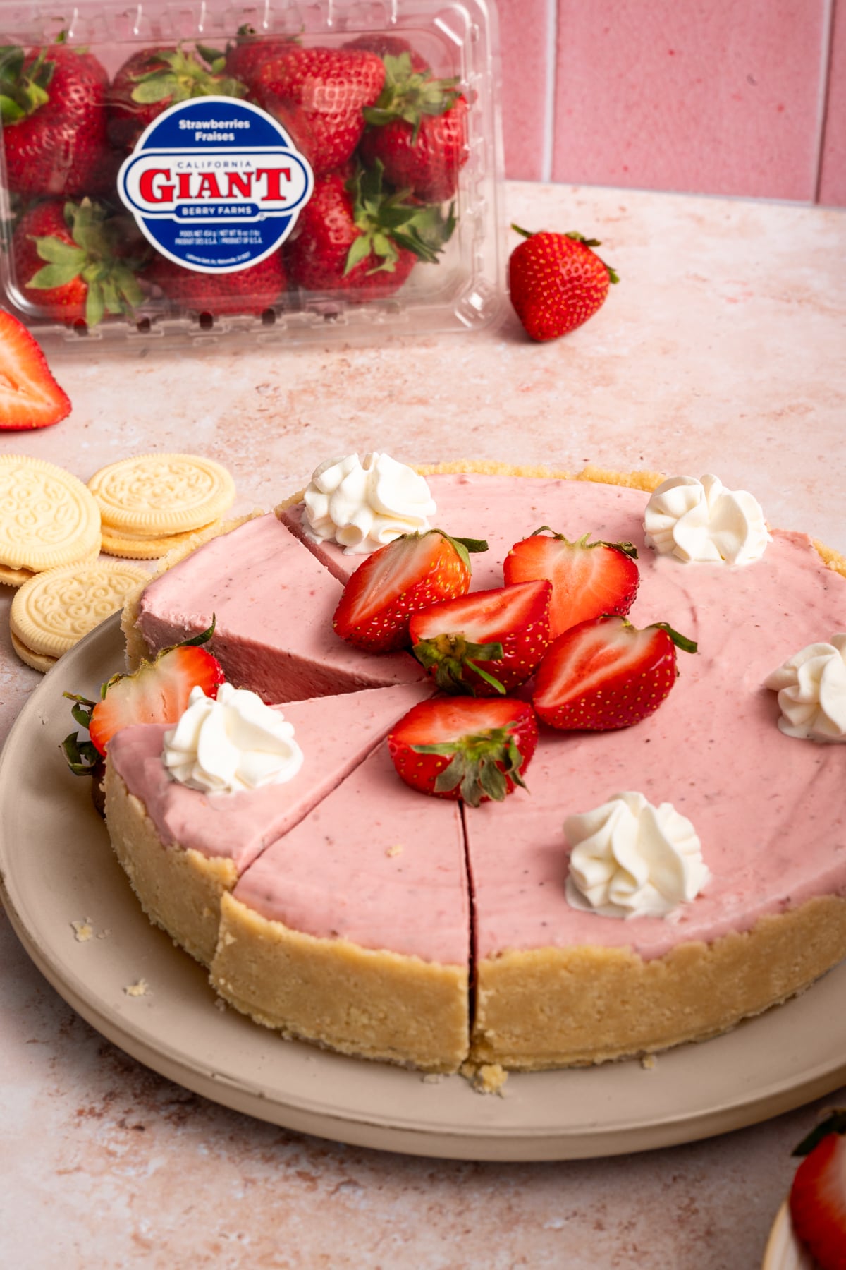 no bake strawberry cheesecake with fresh strawberries and piped whipped cream with vanilla creme cookies.