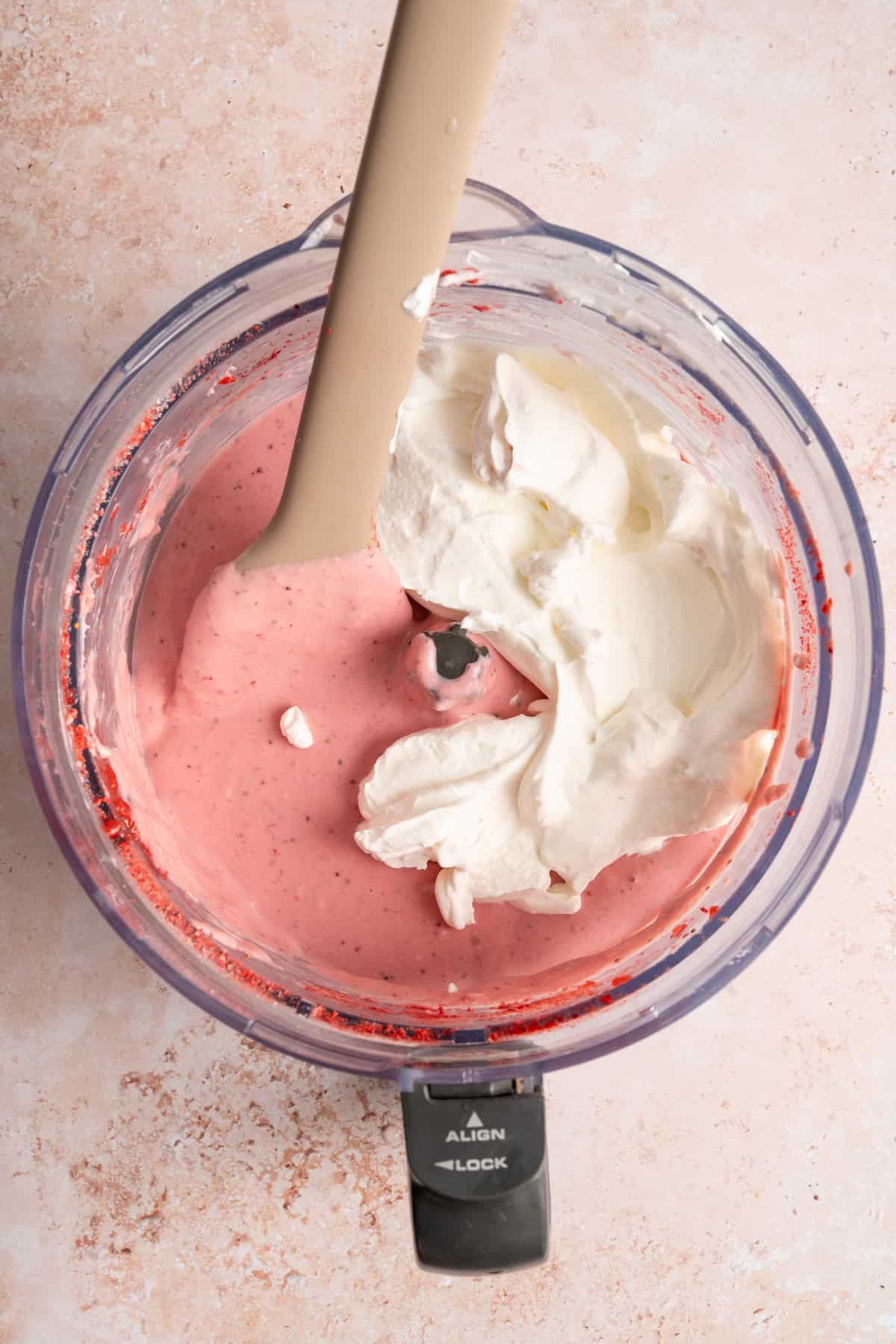 whipped cream stirring into strawberry cheesecake batter.