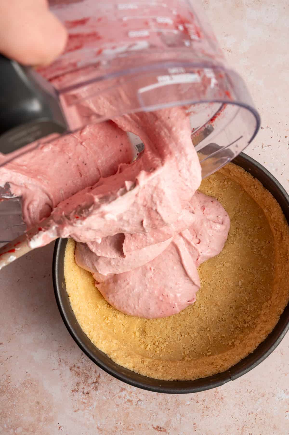 no bake cheesecake batter pouring into pan.