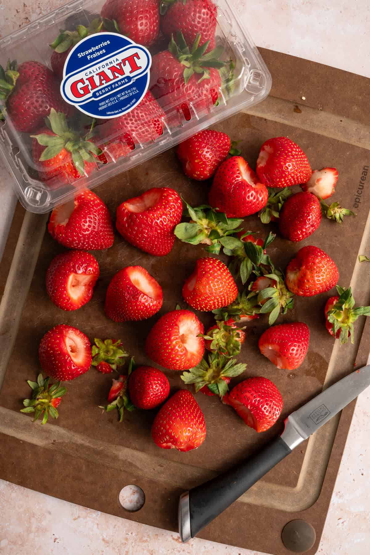 sliced strawberries on cutting board next to California Giant clamshell.