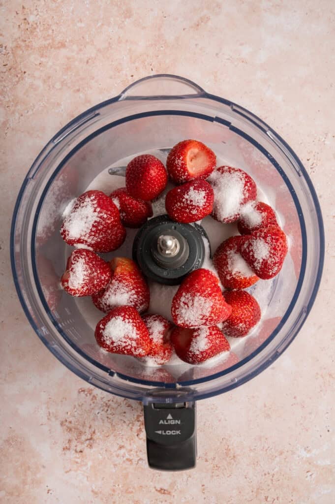 strawberries and sugar in food processor bowl.