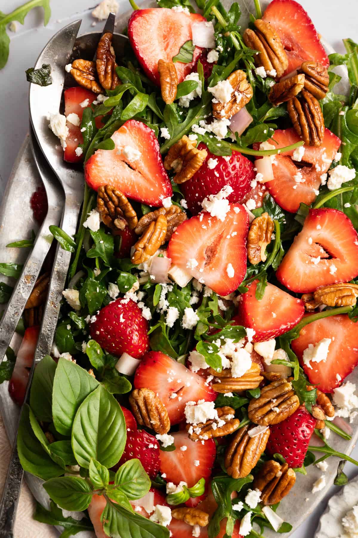overhead view of strawberry arugula salad with feta and pecans.