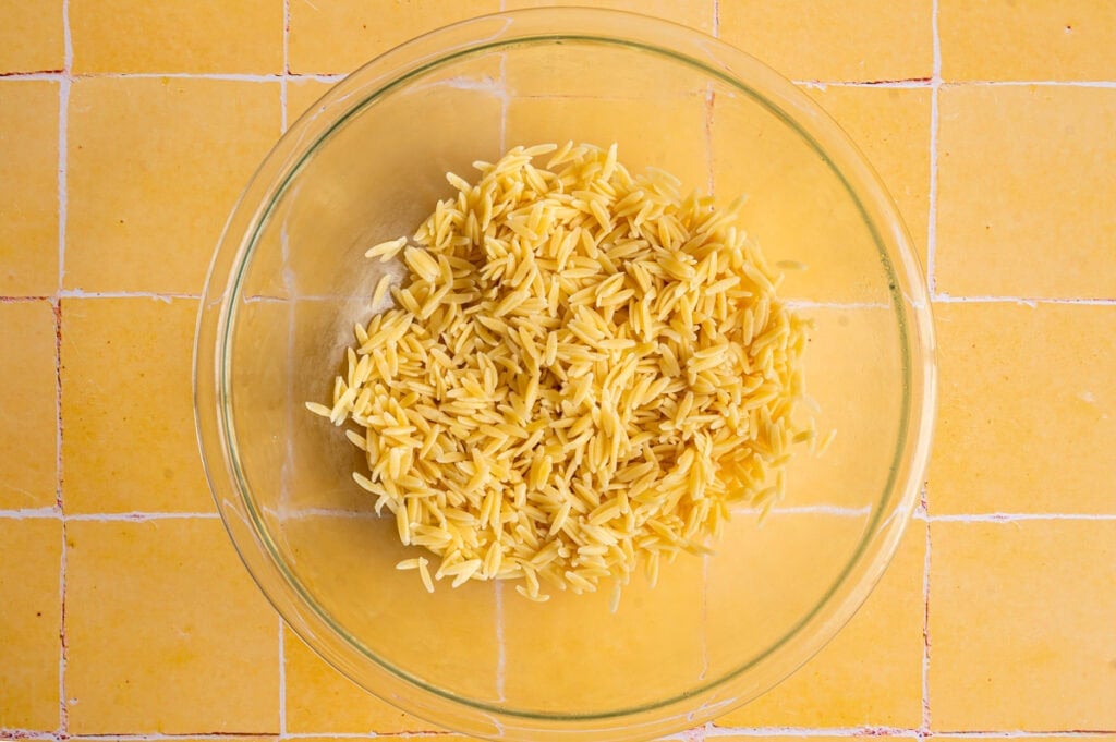 overhead view of orzo cooling in large glass bowl.