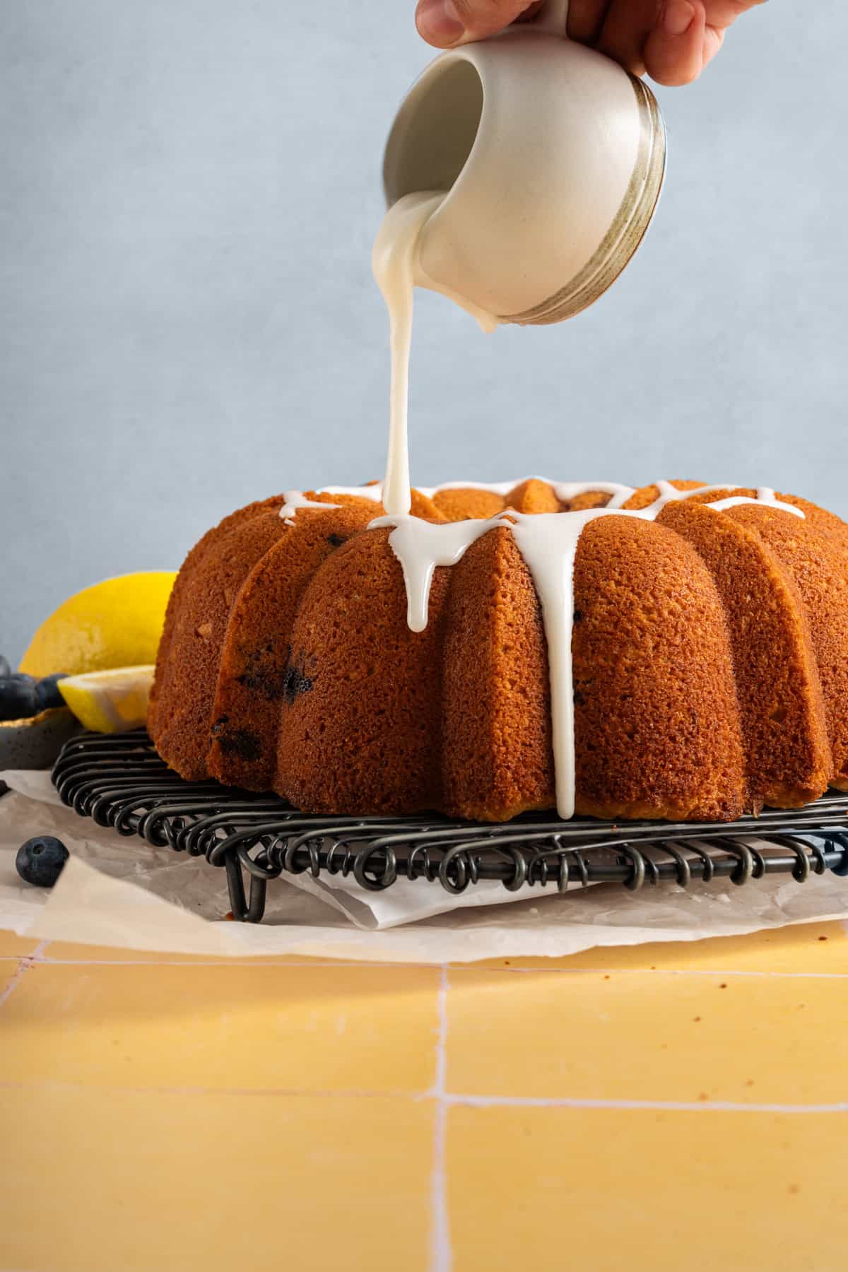 hand pouring glaze over cooled bundt cake.