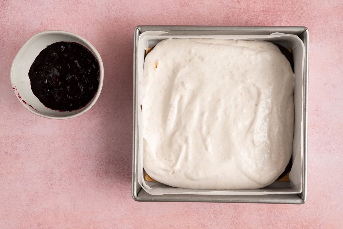 whipped protein topping in square pan next to berry compote.