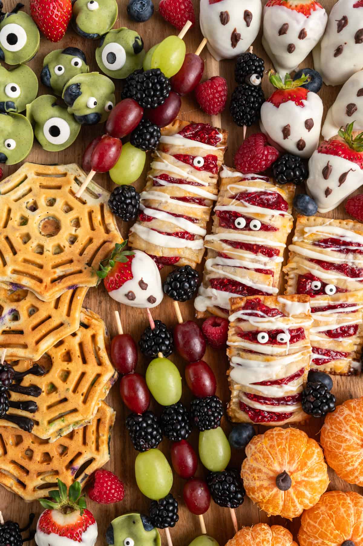healthy halloween snack ideas like chocolate covered strawberry ghosts, mummy hand pies, spider waffles, blackberry spiders and clementines.